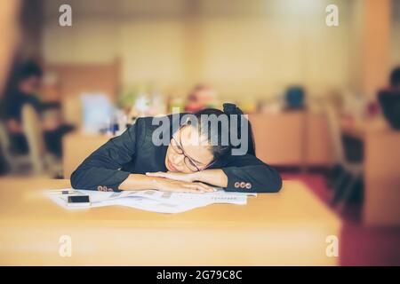 Business woman sleep on desk after Serious tired and headache from analyzing graph and chart document on office desk.Dramatic moment.Split tone instag Stock Photo