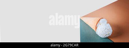 Ice cream in a waffle cone lies on craft paper on white background. Banner. Copy space. Place for text. Stock Photo