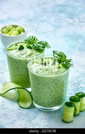 Cucumber Gazpacho - cold summer soup with basil in glasses on light background. Stock Photo
