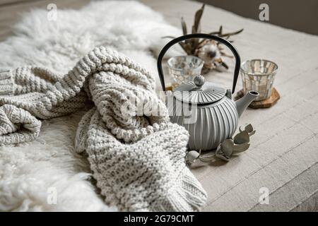 Close-up of teapot in scandinavian style with tea with knitted element and decor details. Stock Photo