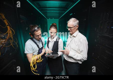 High angle portrait of people using tablet in server room while doing maintenance work in data center, copy space Stock Photo