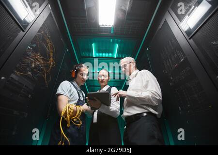 Low angle portrait of people using tablet in server room while doing maintenance work in data center, copy space Stock Photo