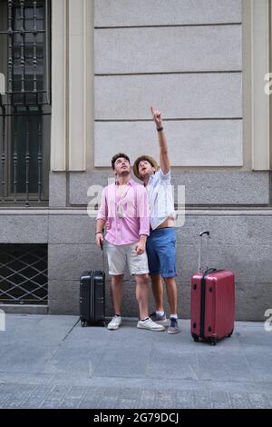 Two tourists looking and pointing up surprised in a city street. Stock Photo