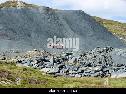 Green slate quarry in Honister Pass in the English Lake District with spoil heap burying quarry buildings - Cumberland UK Stock Photo