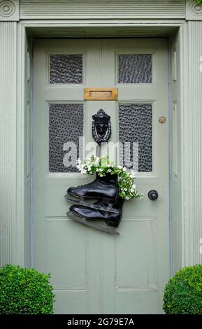 unusual ice skates flower container fixed to house front door, north norfolk, england Stock Photo