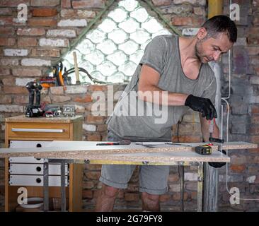 Carpenter doing wood work using clamping hand tool in his workshop. Stock Photo