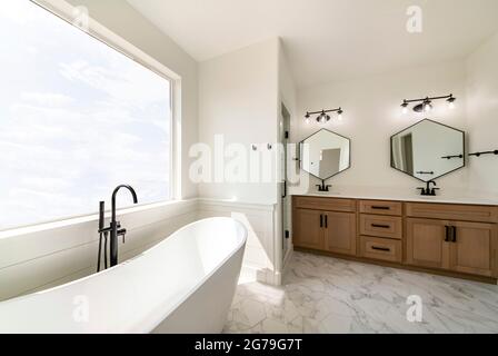 Luxurious bathroom interior with hexagon cut tile flooring and large picture window with sky view Stock Photo