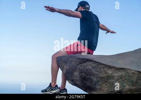 A man enjoying the view to the wild beaches from a rock on the top of the Pedra do Telegrafo mountain, Barra de Guaratiba, Rio de Janeiro, Brazil. Shot with Leica M10 Stock Photo