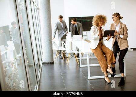 Pretty young women using digital tablet in modern office in front of their team Stock Photo