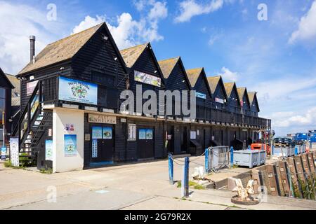 Sea food shops in Black painted fishermans huts and oyster sheds in Whitstable Harbour Whitstable Kent England UK GB Europe Stock Photo