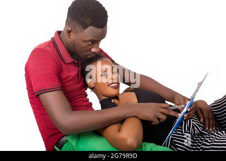 young man sitting on the ground showing something on a block - notes to his girlfriend who smiles. Stock Photo