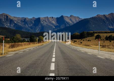 Straight road from La Quillane to Les Angles (France). At the background, some mountains from Pyrenees Orientales Stock Photo