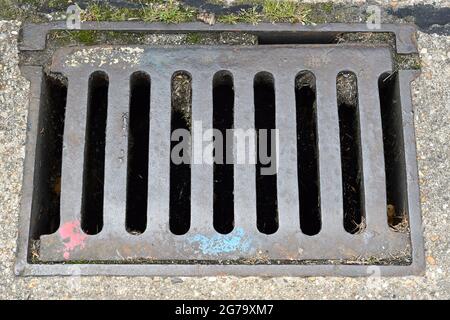 An old iron drainage grate on the side of road Stock Photo