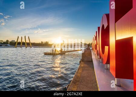 Vienna, sunset at Copa Beach at river Neue Donau (New Danube), partying people on bath raft, in front sculpture 'Copa Beach' in 22. Donaustadt, Wien, Austria Stock Photo