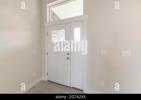 Interior of a white wooden front door with side panel and top transom window Stock Photo