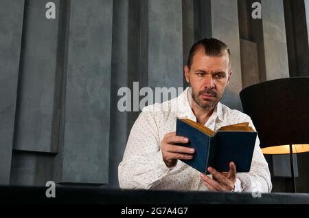 Portrait of man who reads book in the modern room. Knowledge and experience. Stock Photo