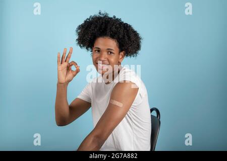 Successful Covid-19 vaccination. Vaccinated Latino man gesture okay and showing arm with a plaster after Vaccine injection. Stock Photo