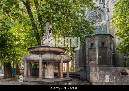 Fountain at the Sankt-Anna-Kirche with chestnut trees in bloom, Munich. Stock Photo