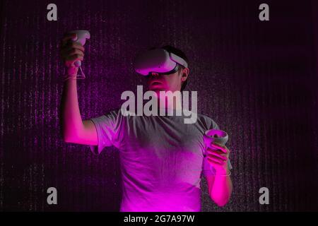 Young caucasian man 25-30 years using virtual reality headset. VR, future, gadgets, technology concept in neon light. Stock Photo