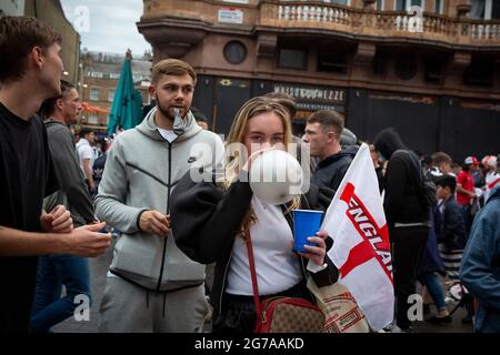 A young woman inhales nitrous oxide, also known as laughing gas ahead of the Euro 2020 Final England vs. Italy Stock Photo