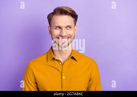 Photo of funny tricky young gentleman dressed yellow shirt smiling looking empty space isolated violet color background Stock Photo
