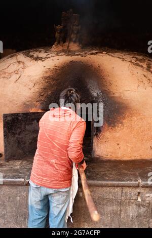 Pisac, Peru - July 29 2010: Local Man Baking Bread in a Traditional, Wood Fired Horno Oven. Stock Photo