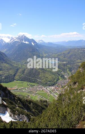 View from Gamseck above the Mittenwalder Hütte, overview of the Mittenwald area, the Wettersteingebirge on the left, the Kranzberg on the right, the Lautersee in between, in the spring against a blue sky, woken atmosphere, atmospheric, the Estergebirge in the background Stock Photo