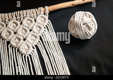 Decorative handmade stylish cotton macrame decoration, hobby interior for hanging on black background. DIY boho home interior decor, wall hanging deco Stock Photo