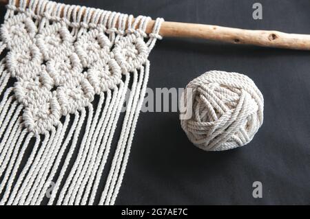 Decorative handmade stylish cotton macrame decoration, hobby interior for hanging on black background. DIY boho home interior decor, wall hanging deco Stock Photo