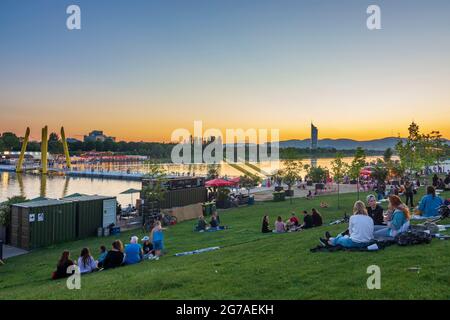 Vienna, sunset at Copa Beach, river Neue Donau (New Danube), people on meadow, view to Wienerwald in 22. Donaustadt, Wien / Vienna, Austria Stock Photo