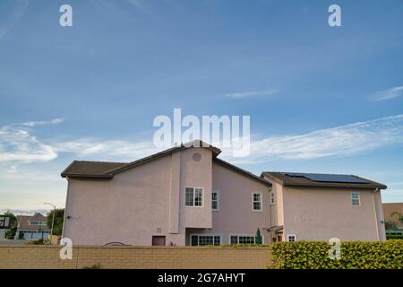 Two storey house exterior with beige wall and solar panels on the pitched roof Stock Photo