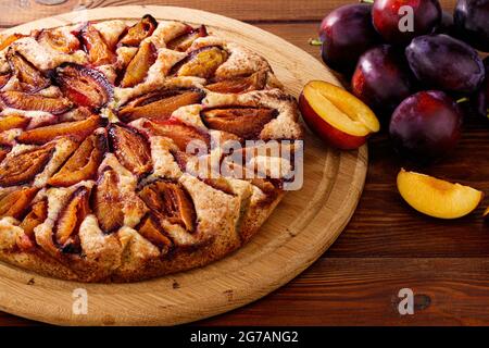 Homemade baking. Plum pie and plums, on wood background. Stock Photo