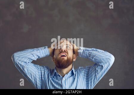 Frustrated upset business man holding head with hand looking up studio shot Stock Photo