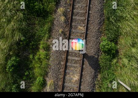 A person stands with an umbrella on a disused railroad track Stock Photo