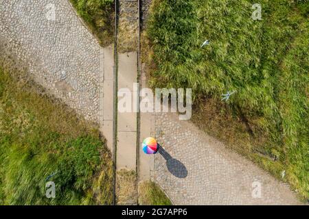 A person stands with an umbrella on a disused railroad track Stock Photo