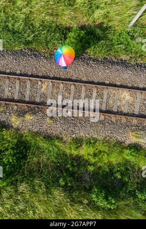 A person stands with an umbrella on a disused railroad track Stock Photo