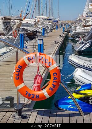 Calpe Spain - August 24 2016; Long marina pier with boats moored along both sides and orange buoy with words Real Club Nautico Calpe, famous  boating Stock Photo