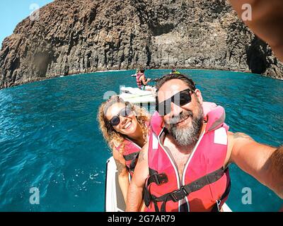 Cheerful pretty man and woman together on a jet sky having fun in summer holiday vacation - travel and happy lifestyle young people - selfie picture and smiles - blue ocean and coastline Stock Photo