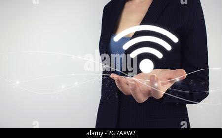 Free WiFi network signal technology internet concept. Hand hold digital hologram WI FI icon on grey background Stock Photo