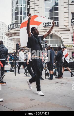 London | UK - 2021.07.12: Black English fan with flags going to Leicester Square to watch the Final Euro 2020 Football game Stock Photo