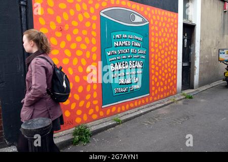 Young woman walking past Baked Beanz tin mural artwork on the side of a building in Walthamstow East London E17 UK  England  KATHY DEWITT Stock Photo