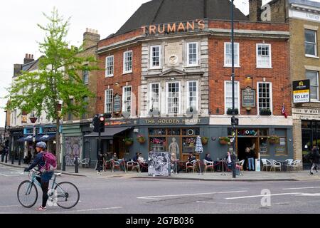 Cyclist on bike outside Truman's pub The Golden Heart on the corner of Commercial St & Hanbury Street near Spitalfields Market London E1  KATHY DEWITT Stock Photo