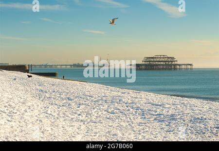 Snow on the beach, Brighton, England, with the Brighton Palace Pier and remains of the West pier behind. Stock Photo
