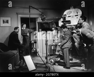 SPENCER TRACY MYRNA LOY director SAM WOOD and Cinematographer JAMES WONG HOWE and Camera Crew on set candid during filming of WHIPSAW 1935 director SAM WOOD wardrobe Dolly Tree cinematographer James Wong Howe Metro Goldwyn Mayer Stock Photo