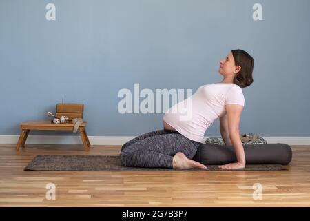 Pregnant woman practicing yoga in suptha virasana exercise Stock Photo