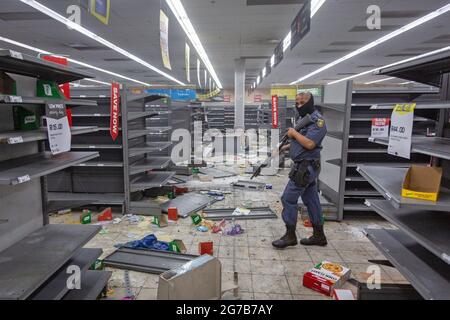 (210712) -- JOHANNESBURG, July 12, 2021 (Xinhua) -- A police officer walks in a looted shop in Johannesburg, South Africa, on July 12, 2021. Soldiers have been deployed in KwaZulu-Natal and Gauteng provinces to deal with violent protests and looting, the South African army said on Monday. Police said six people were killed and 219 people arrested over the weekend in Gauteng and KwaZulu-Natal following violent protests after former president Jacob Zuma was jailed for 15 months for contempt of court. Hundreds of shops and businesses across the two provinces were looted. (Photo by Yeshiel/Xinhua) Stock Photo