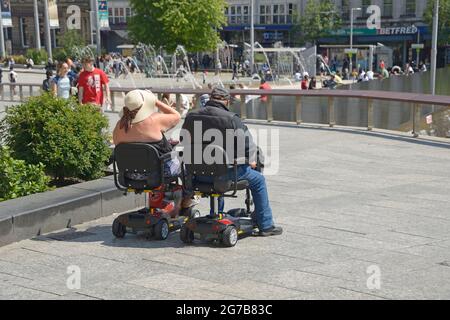 Couple on mobility scooters, parked side by side. Stock Photo