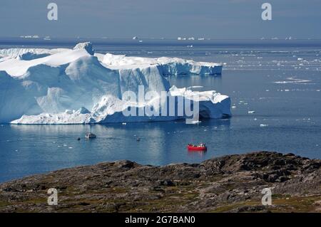 Red boat in front of big icebergs, Sermeq Kujalleq, Disko Bay, Greenland, Denmark Stock Photo