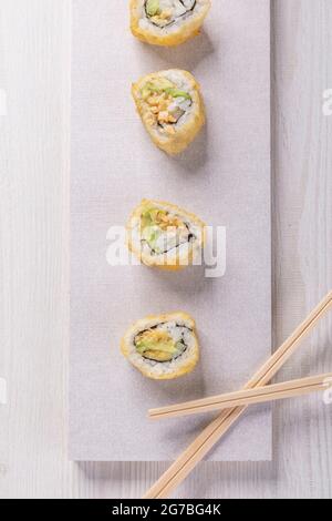 gourmet plate with four sushi rolls with some wooden chopsticks, food texture in studio, delicious traditional dish Stock Photo