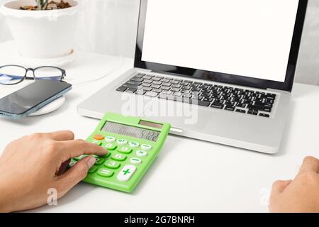 Accountant working and analyzing financial calculating with calculator and laptop computer income-expenditure at office desktop, Business financial an Stock Photo